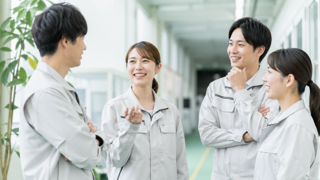 明るく整理された事務所の廊下で、４名の作業者が談笑している様子